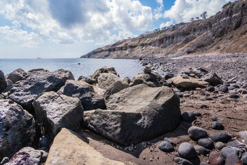 crystal clear sea caresses the dark rocks of the coast of the island of santorini