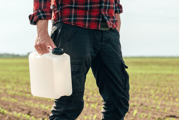 Corn crop protection concept, male farmer agronomist holding jerry can container canister with...