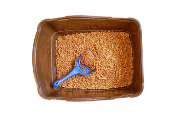 Brown toilet tray for cat with wood pellets and scoop, isolated on a white background. The cats...
