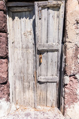 Wooden door worn and rusted by time in an ancient temple in santorini