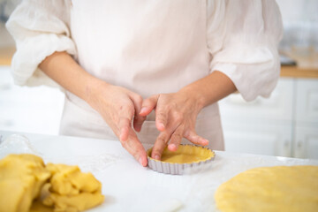 Cooking and home concept - close up of female hands making tart from fresh dough at home. Hands...