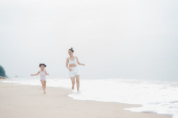 happy time of mom and daughter in dress white walking and run play on the beach morning time with blur background