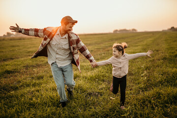 Happy family on the summer walk! Father and daughter walking outdoors on an animal field and...