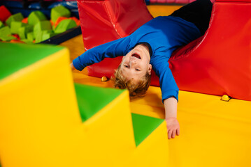 Active children's games in play center, playroom, playground. Little boy is playing among soft blocks.