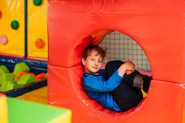 Active children's games in play center, playroom, playground. Little boy is playing among soft...