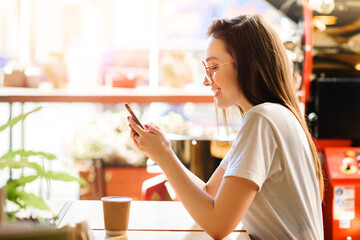 Young beautiful woman with smartphone in cafe at the table.