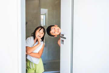 Fototapeta na wymiar Family brushing teeth in the bathroom. Two kids at the door to the bathroom.