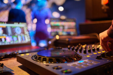 An expert adjusting audio mixing console with white blank screen laptop on control desk.