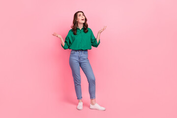 Full size photo of unhappy dissatisfied upset girl dressed jeans green shirt look up empty space asking isolated on pink background