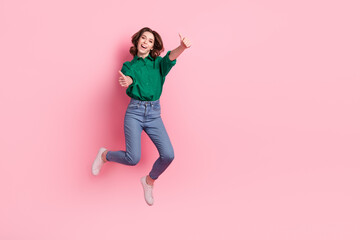 Fototapeta na wymiar Full length photo of satisfied pretty cute woman wear jeans green shirt flying showing thumbs up scream yeah isolated on pink background