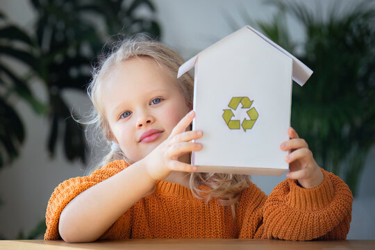 Girl holding house model with recycling logo