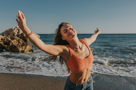 Happy woman with arms raised enjoying at beach