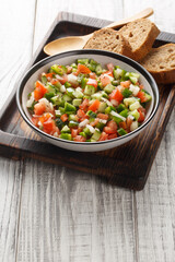 Pipirrana typical Malaga Spanish salad with onion, tomato, green pepper and cucumber closeup on the plate on the table. Vertical