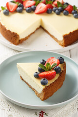 Piece of Classic New York Cheesecake with fresh berries closeup on the plate on the wooden table. Vertical