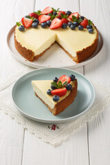 Classic Freshly New York Cheesecake with fresh berries and mint closeup on the plate on the wooden table. Vertical