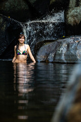 Fototapeta na wymiar a beautiful girl in a bikini takes a refreshing swim at a waterfall at cedar creek swimming holes near brisbane and gold coast in queensland, australia; hidden gems of australia