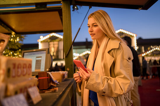 Young woman holding smart phone ordering food at concession stand