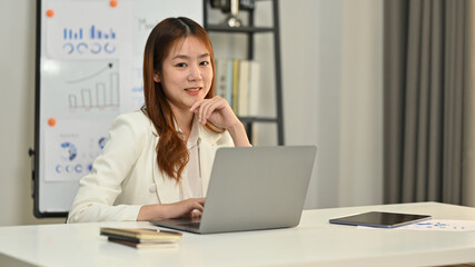 Portrait of young businesswoman, small business owner working online on laptop computer at office