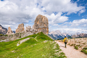 Young female is admiring Cinque Torri in Dolomites mountains in Italy - obrazy, fototapety, plakaty