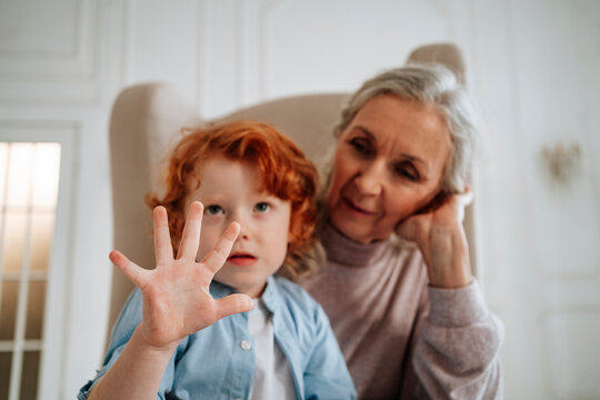 Boy sitting with grandmother gesturing at home