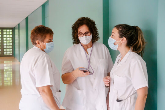 Nurses wearing protective face masks talking to each other at hospital