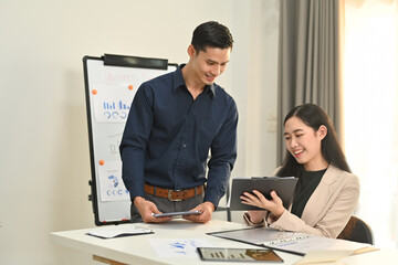 Image of successful partnership looking at digital tablet, discussing business plan at meeting