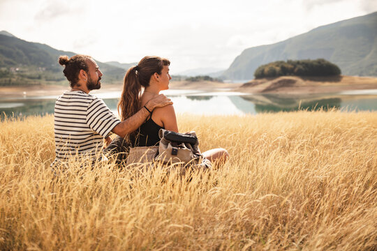 Man sitting with arm around girlfriend on dry grass