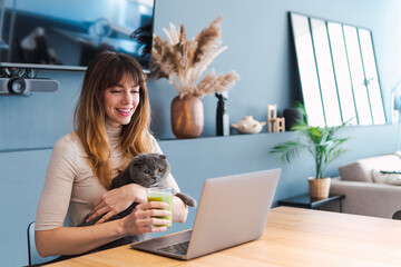 Happy woman watching laptop with cat at home