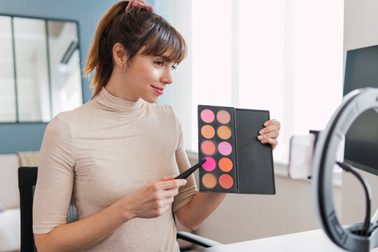 Influencer showing make-up palette on tutorial at home