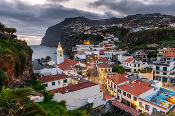 Fototapeta na wymiar Cityscape of Camara de Lobos at dusk illuminated architecture of the seaside town in Madeira island, Portugal