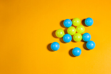 Yellow and blue little balls on orange background, copy space, space for text, communication business school education concept 