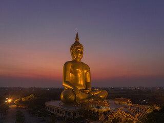 aerial view The moon on the head of golden big Buddha. 
the Biggest Buddha in the world at wat Maung Angtong Thailand.
scenery sky in twilight background.the one famous landmarks in Thailand.
