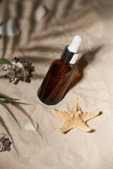 Summer sunscreen essence on sand background with seashells and starfish.