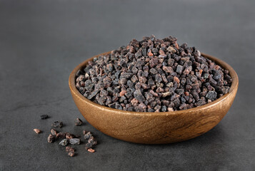 Himalayan black salt in a wooden bowl on a gray background. Spices background.