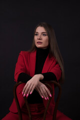 Fototapeta na wymiar Portrait of a businesswoman in a red suit on a black background.