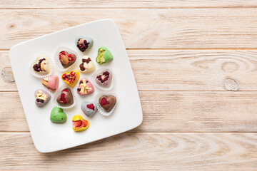 Plate with different chocolate on colored background. Assortment of fine chocolates top view vith copy space Health and obesity concept