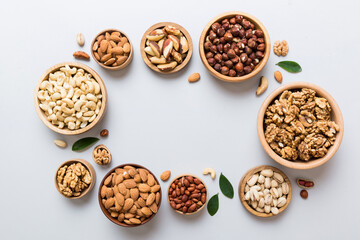 mixed nuts in wooden bowl. Mix of various nuts on colored background. pistachios, cashews, walnuts, hazelnuts, peanuts and brazil nuts