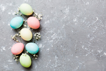 Happy Easter composition. Easter eggs on colored table with gypsophila. Natural dyed colorful eggs background top view with copy space