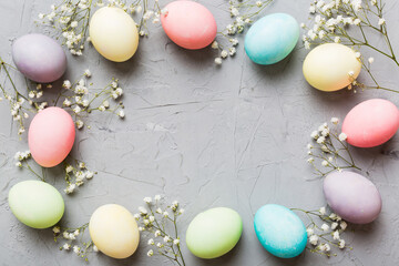 Happy Easter composition. Easter eggs on colored table with gypsophila. Natural dyed colorful eggs background top view with copy space