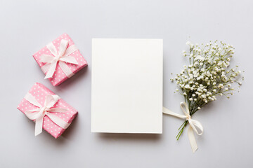 Wedding mockup with white paper list and flowers gypsophila on colored table top view flat lay. Blank greeting cards and envelopes. Beautiful floral pattern. Flat lay style
