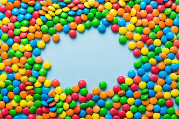 Obraz premium Mixed collection of colorful candy, on colored background. Flat lay, top view. frame of colorful chocolate coated candy