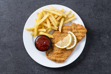 Wiener schnitzel with fried potatoes on black slate surface.typical vienna food. Top view