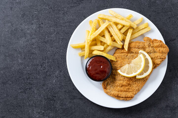 Wiener schnitzel with fried potatoes on black slate surface.typical vienna food. Top view. Copy space