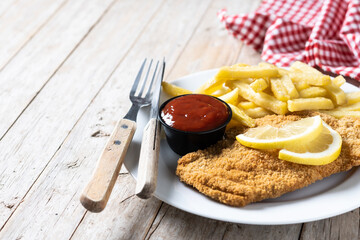 Wiener schnitzel with fried potatoes on wooden table.typical vienna food. Copy space
