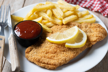 Wiener schnitzel with fried potatoes on wooden table.typical vienna food