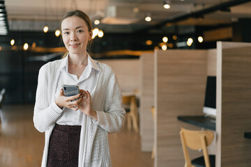 Beautiful young caucasian woman working with smart phone in office	