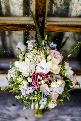 Bunter Brautstrauß vor einem alten Holzfenster