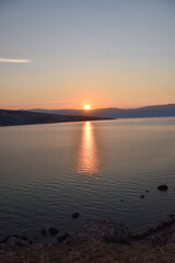 Vibrant sunset descending on the horizon, sea in golden colors, small waves gently touching the sands,