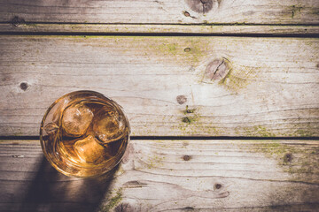 Overhead shot of glass of whiskey on wooden table