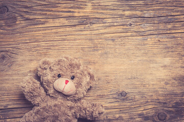 Brown teddy bear over wooden background
